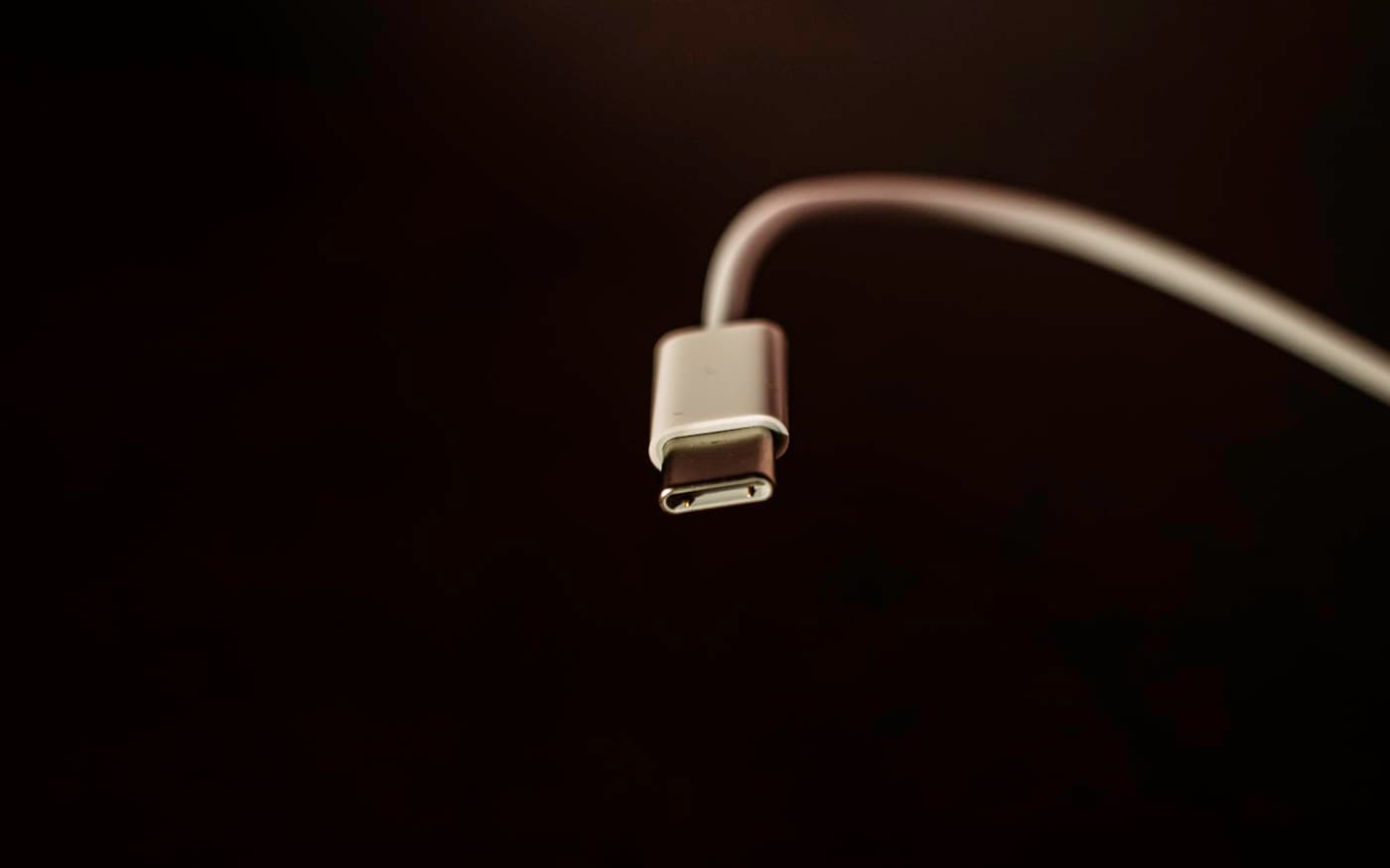 A USB-C connector on a black surface, its contacts catching a single light.