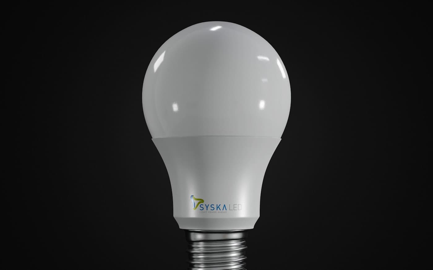 A smart bulb standing on a near-black surface under one soft light.