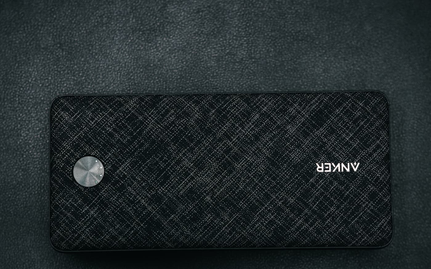 A fabric-wrapped power bank lying on a dark textured surface.