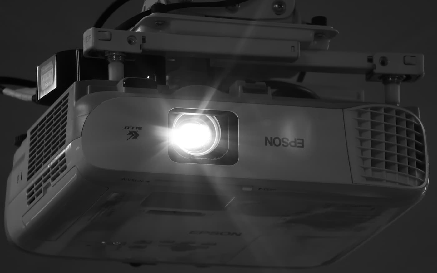 A projector's lamp burning in a dark room, photographed in black and white.